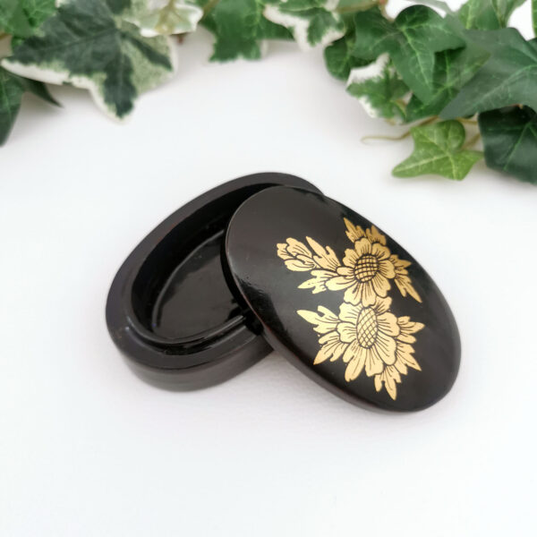 Petite boîte ovale laquée noire à motif doré floral, typique des souvenirs asiatiques des années 60 à 80