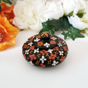boîte ronde vintage en céramique noire avec petites fleurs orange et blanches
