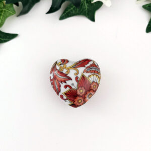 Mini-boîte en porcelaine blanche en forme de cœur, décorée de fleurs brun et jaune, vue de dessus.