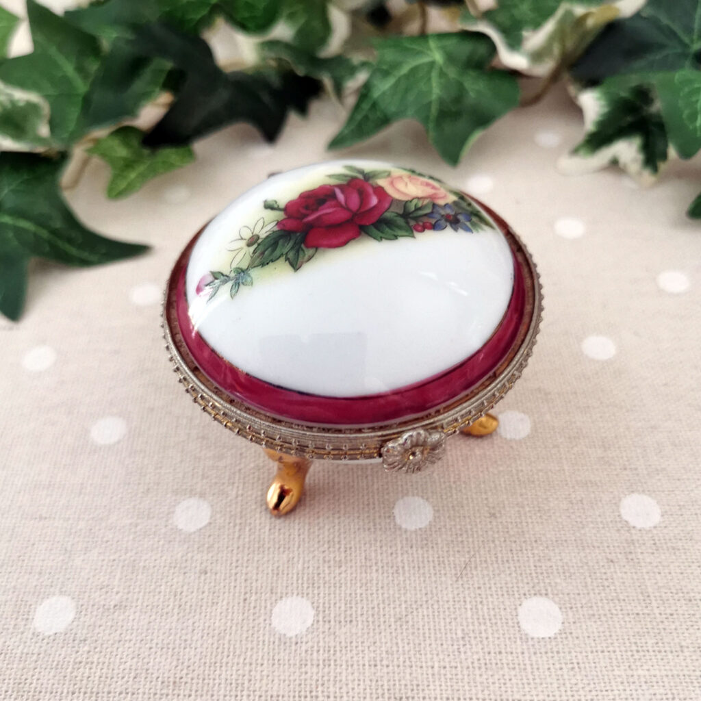 Boîte ronde en porcelaine blanche à pieds dorés, décor floral sur couvercle et fermeture en laiton