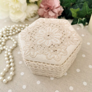 Boîte hexagonale en tissu crème avec détails brodés et finition dentelle, ambiance romantique