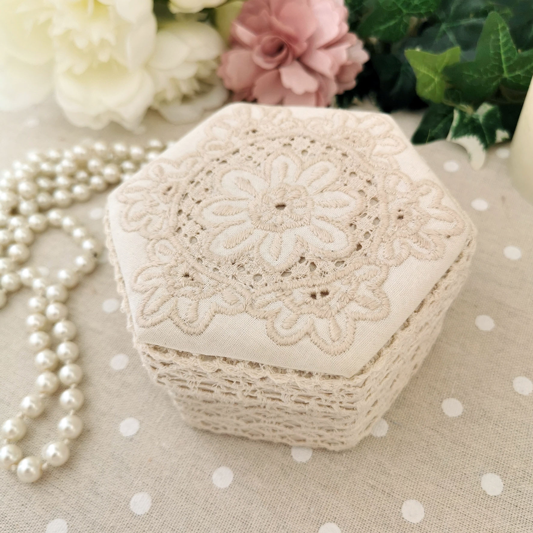 Boîte hexagonale en tissu crème avec détails brodés et finition dentelle, ambiance romantique
