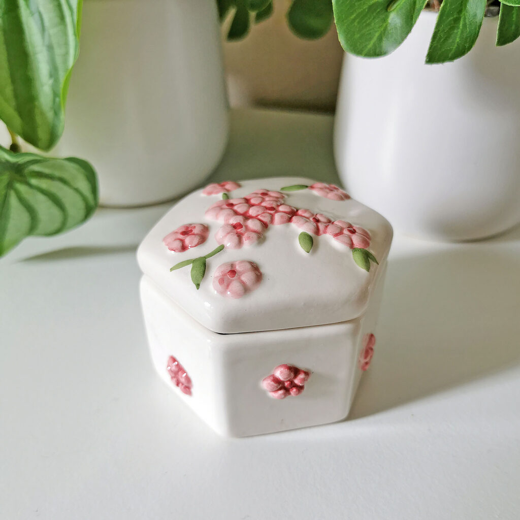 Petite boîte hexagonale blanche en céramique décorée de fleurs roses en relief