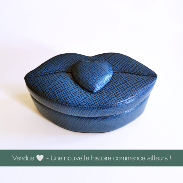boîte bleue en forme de lèvres avec cœur central en relief, fermée